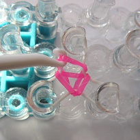 7. Přes všechny tři kolíky navlékneme růžovou gumičku, opakujeme předchozí krok a střídáme barvy gumiček.